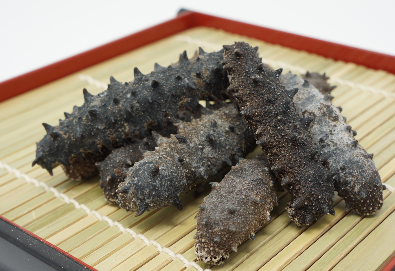 Dried sea cucumber holothurian seafood products on bamboo tray for premium Asian seafood commodity photography